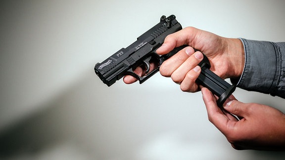 Hände laden eine Schreckschuss-Pistole «Walther P22» mit einem Magazin