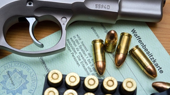 Eine Kaliber 9 mm Pistole, Patronen und ein Magazin liegen auf einer Waffenbesitzkarte