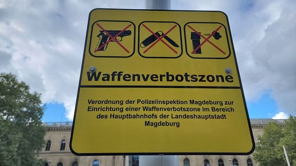 Ein Schild vor dem Hauptbahnhof Magdeburg auf dem Waffenverbotszone steht.