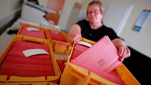 Eine Frau aus der Poststelle der Verwaltung des Landkreises Harz sortiert eingehende Briefwahlumschläge für die Europawahl nach Wahlbezirken. 