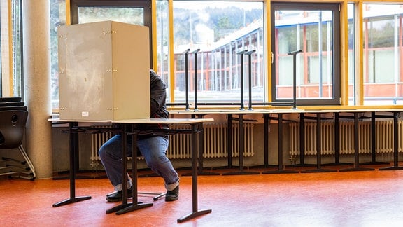 Ein Wähler sitzt 2021 im Wahllokal in einem Gymnasium und gibt seine Stimme ab.