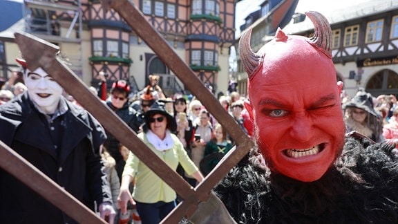 Im Kostüm stehen Walpurgisbesucher in Wernigerode vor der Erstürmung des Rathauses auf dem Marktplatz.
