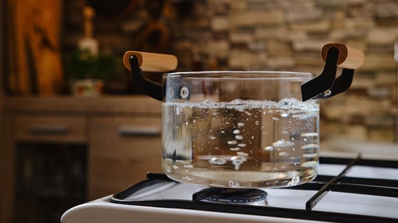 Wasser kocht in einem durchsichtigen Glastopf auf dem Herd