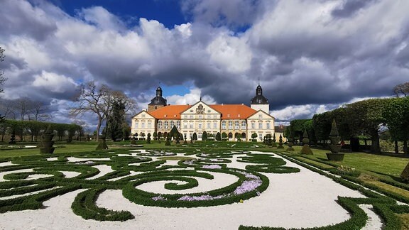 Schloss Hundisburg bei wolkigem Himmel mit Gartenanlage im Vordergrund