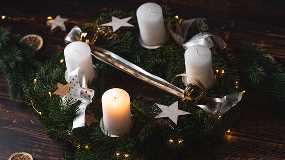 Eine Kerze brennt zum 1. Advent auf einem festlichen Adventskranz zur Adventszeit 