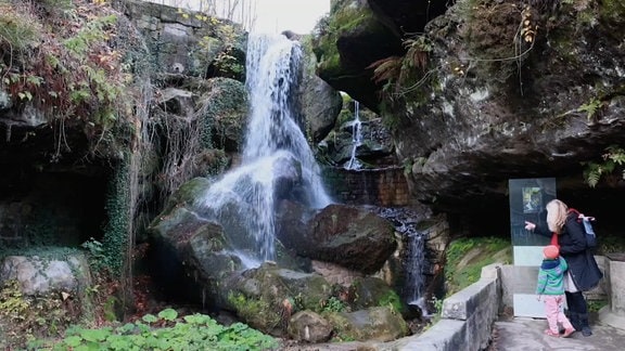 Der Lichtenhainer Wasserfall. Davor eine Mutter mit kleinem Kind.