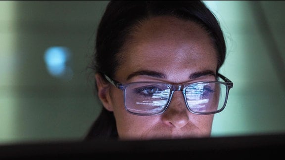 Eine Frau mit Brille schaut in einen Laptop.