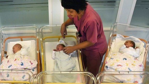 Stationsschwester Katrin steht an den Bettchen von wenige Stunden alten Babys in der Geburtenstation.
