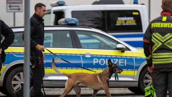 Ein Polizist geht mit einem Sprengstoffsuchhund zum Schulgebäude.