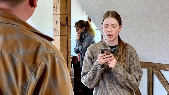 Eine junge Frau schaut auf ihr Smartphone.