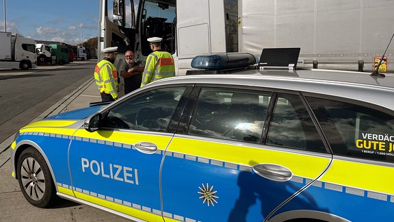 Polizeifahrzeug vor Polizisten vor LKW