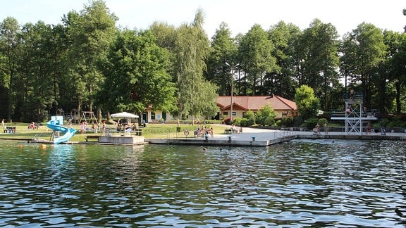 Blick über das Wasser auf Rutsche und Sprungturm 