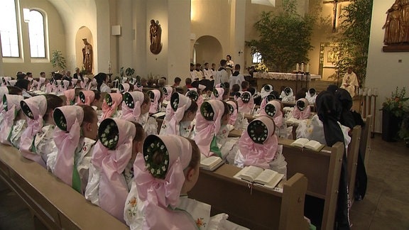 In der Ralbitzer Katharinenkirche sitzen in festlicher Tracht gekleidete Mädchen und schauen zum Altar
