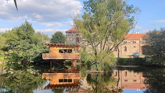 Ein Haus steht auf Stahlstützen in einem Teich.