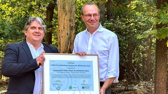 Die Königsbrücker Heide nördlich von Dresden hat als bundesweit erstes Terrain die internationale Anerkennung als Wildnisgebiet erhalten. Sachsens Umweltminister Wolfram Günther (rechts) erhielt die Urkunde von Professor Eick von Ruschkowski von der Weltnaturschutzunion (IUCN).