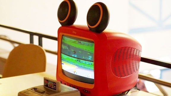 Supernitendo vor einem roten Röhrenfernseher mit Lautsprechern die wie Ohren angebracht sind