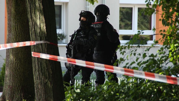 Zwei SEK-Beamte stehen hinter einem Baum. 