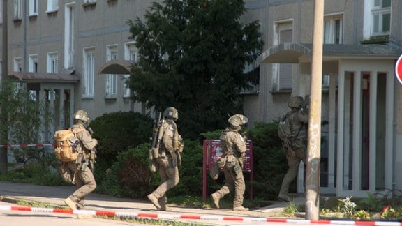  Mehrere ESK-Beamte laufen in ein Gebäude.