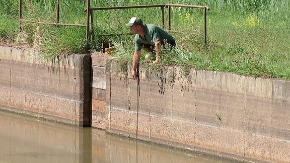 Ein Mann misst die Wassertiefe.