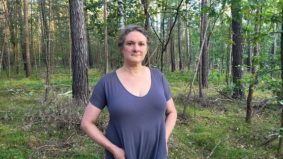 Ein Frau steht im Wald bei Radeburg.