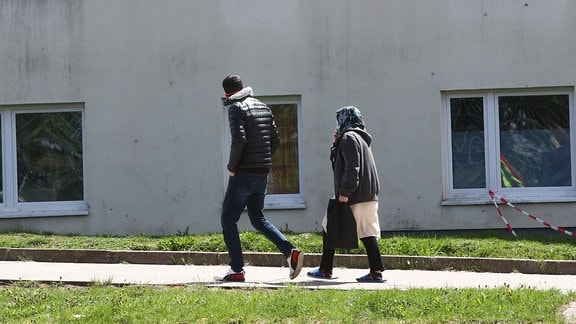 Asylbewerber gehen auf dem Gelände der Erstaufnahmeeinrichtung des Landes Thüringen spazieren.
