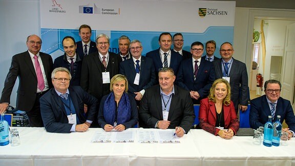 Hinter einem Konferenztisch stehen und sitzen Vertreter von 14 europäischen Kohleregionen