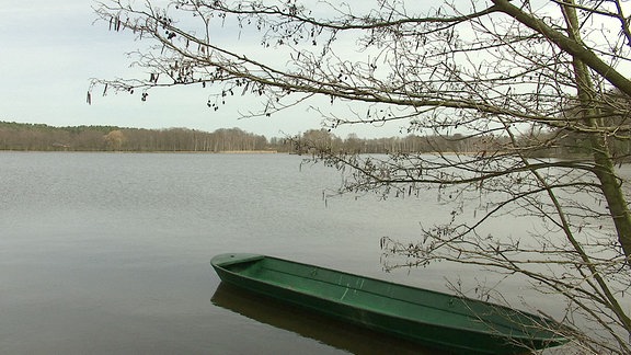 Landschaftsaufnahme eines Sees mit einen länglichen Boot im Vordergrund