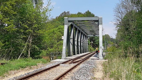 Ein Mann geht über eine eingleisige Eisenbahnbrücke