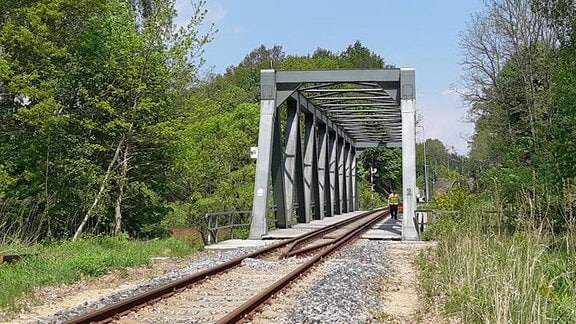 Ein Mann geht über eine eingleisige Eisenbahnbrücke