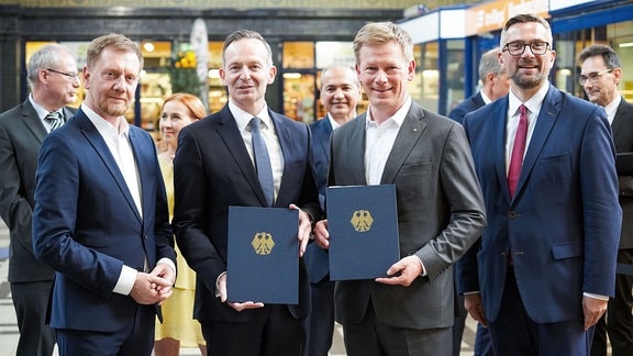 Volker Wissing und DB-Vorstandschef Richard Lutz halten eine unterzeichnete Vereinbarung in den Händen.
