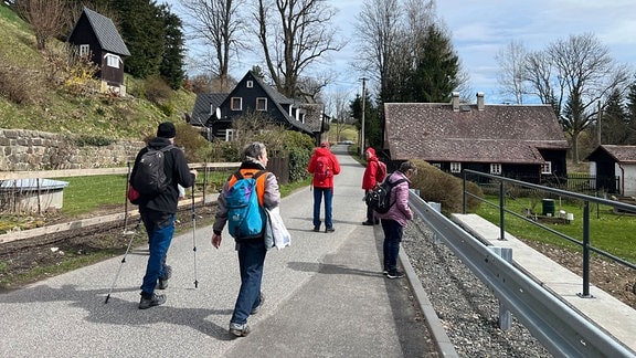 Wanderer aufen auf einer schmalen Straße durch das böhmische Dorf Brtníky.