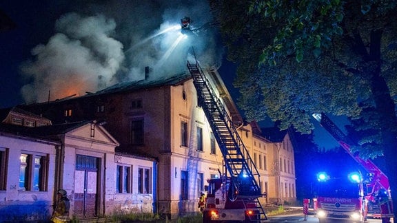 Feuerwehrleute löschen das brennende Bahnhofsgebäude.
