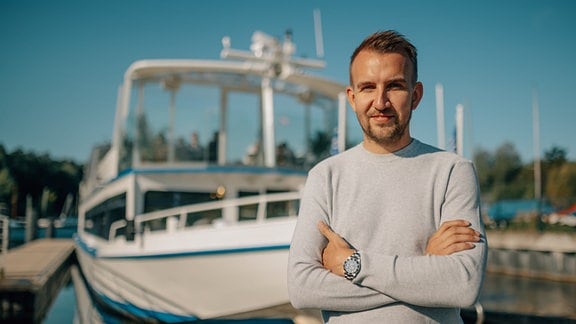 Der Betreiber steht auf seinem elektrischen Fahrgastschiff, der EMS Berzdorf