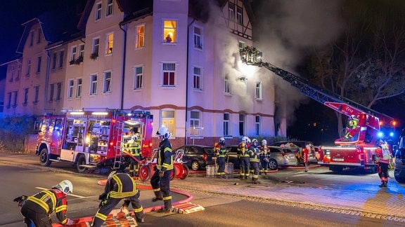 Feuerwehrleute befinden sich im Löscheinsatz vor einem Altbau.