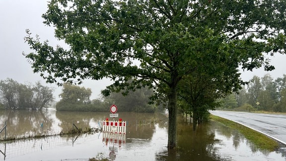 Ein Fluss fließt über ein Feld und eine Straße.