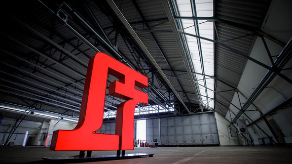 Blick in einen Hangar auf dem ehemaligen Flugplatz Cottbus mit dem großen, roten Logo des Lausitz Festivals darin.