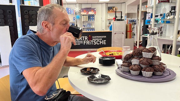 Ein Mann sitzt an einem Tisch und genießt Kaffee und Kuchen