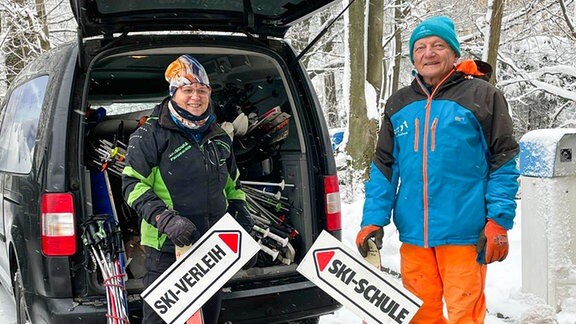 Frau und Mann entladen einen Transporter voller Ski