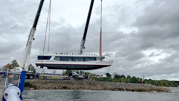 Ein Boot wird mit einem Kran aus einem See gehievt.