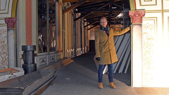 Daniel Morgenroth, ein Mann in hellbraunem Mantel und Jeans steht in einem historischen Gebäude