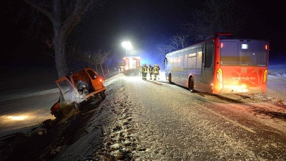 Nächtliche Unfallstelle im Schnee mit einem parkenden Bus und Rettugnskräften