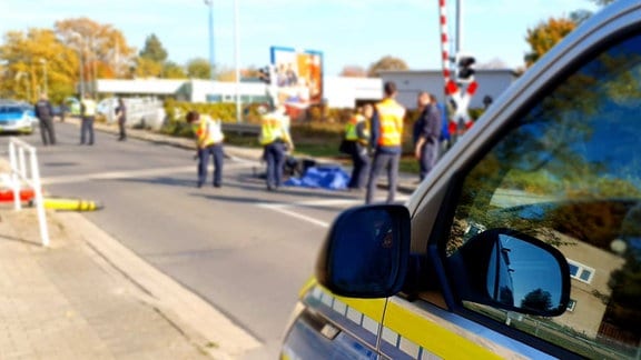 Polizisten sichern einen Unfallort an einem Bahnübergang ab. 