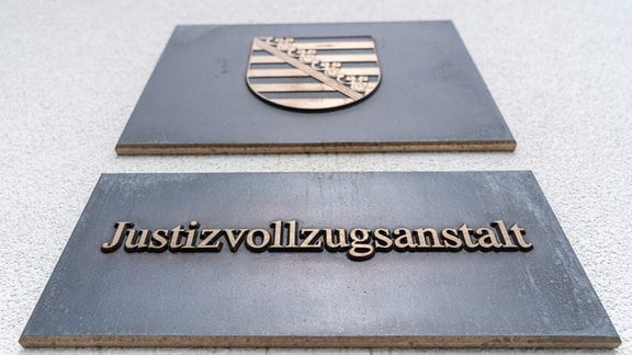 Zwei Schilder mit dem Sachsen Wappen und der Aufschrift Justizvollzugsanstalt sind am Eingang der JVA Chemnitz angebracht.