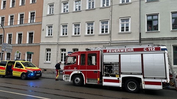 Ein Feuerwehrfahrzeug und ein Notarztwagen stehen vor einem Wohnhaus in Görlitz.