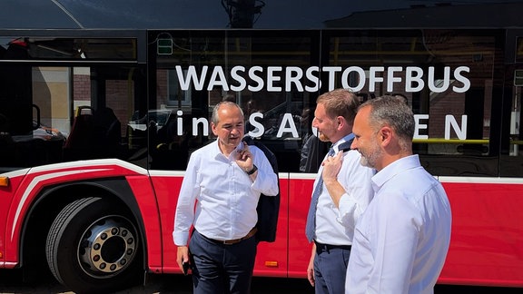 Drei Männer vor einem Bus