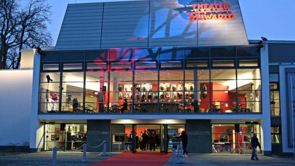 Außenansicht des Theaters in Bautzen: eine Glasfassade, die mit Scheinwerfern angestrahlt wird