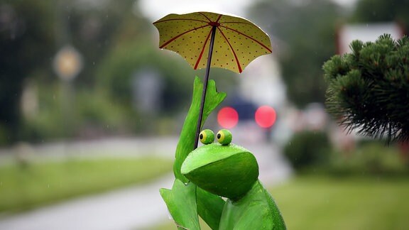 Eine Froschfigur mit einem Regenschirm.