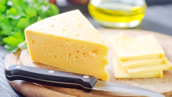 Käse und ein Messer auf einem Holzbrett