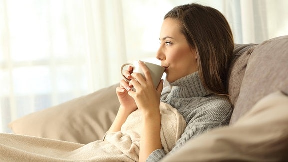 Frau auf Sofa Tee trinken