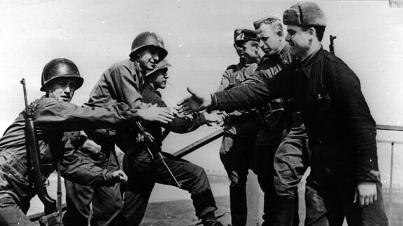 Händedruck zwischen Rotarmisten und US-Soldaten auf der zerstörten Brücke über die Elbe bei Torgau.